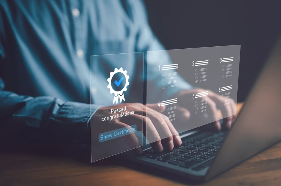 Personne travaillant sur ordinateur portable dans un environnement professionnel intérieur, mains sur clavier, consultation d'interface numérique