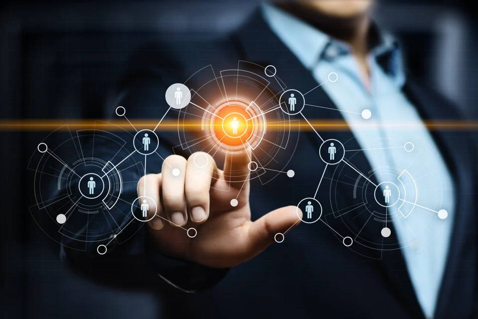 Un homme en costume sombre et chemise claire pointe son index vers une interface numérique holographique